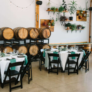 Elegant wedding reception setup at The Barrel Room, a Bend Oregon wedding venue featuring rustic barrels, greenery, and intimate industrial charm.