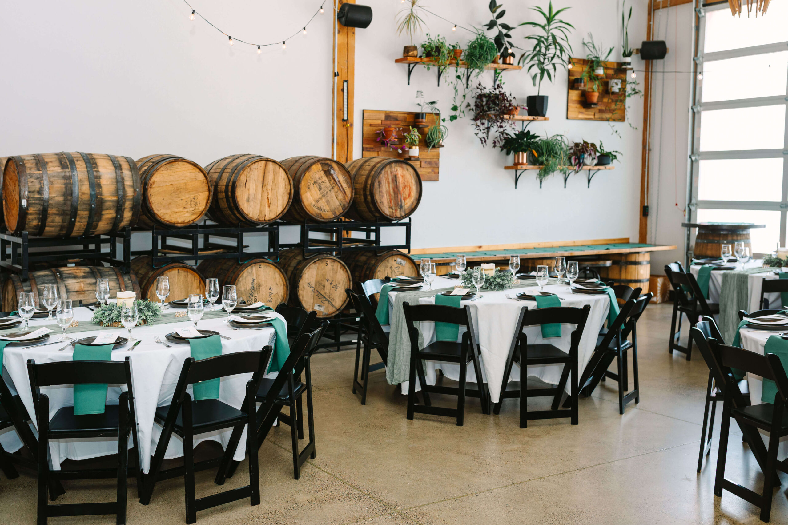 Elegant wedding reception setup at The Barrel Room, a Bend Oregon wedding venue featuring rustic barrels, greenery, and intimate industrial charm.