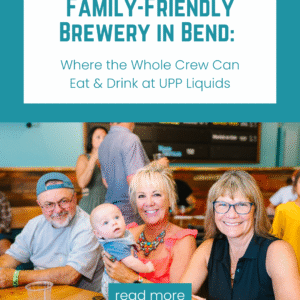 A smiling family with a baby sitting at a table inside a cozy Bend brewery, enjoying food and drinks together in a warm, family-friendly atmosphere.
